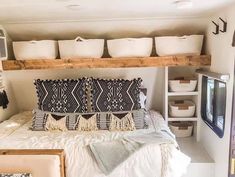 a bed with lots of pillows on top of it in a room filled with shelves