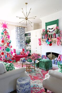 a living room decorated for christmas with pink, green and blue decorations on the tree