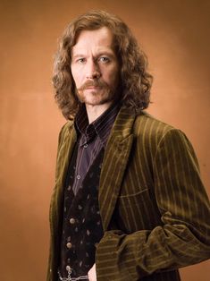 a man with long curly hair wearing a suit and tie, posing for a photo