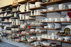 shelves filled with white dishes and plates on wooden shelves next to each other in a room