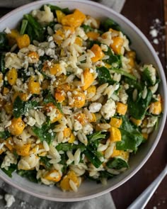 a bowl filled with rice and vegetables on top of a table next to silverware