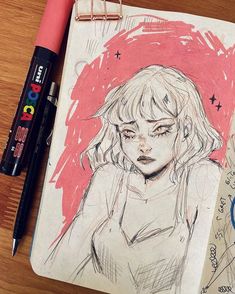 a drawing of a girl with blonde hair and bangs on top of a notebook next to some markers