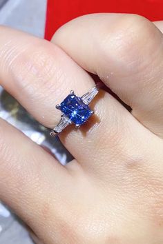 a woman's hand with a ring on it and a blue diamond in the middle