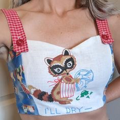 a woman wearing a crop top with a raccoon on it's chest