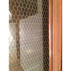 a close up view of a door with chicken wire on the glass and wood frame