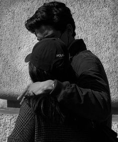 black and white photograph of two people hugging each other on the street with police written on their backs