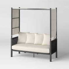 a white couch sitting under a metal frame with pillows on it's back end