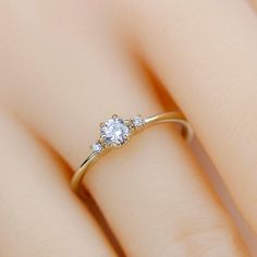 a woman's hand with a diamond ring on top of her finger, showing the center stone