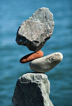 three rocks stacked on top of each other near the water