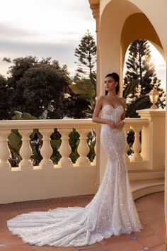 a woman in a wedding dress standing on a balcony with her arms around her waist