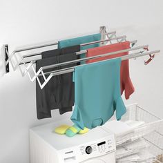 clothes are hanging on a drying rack next to a washing machine