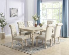 a dining room table and chairs in front of a window with blue drapes on the windowsill