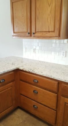 a kitchen with wooden cabinets and white marble counter tops in the middle of the room