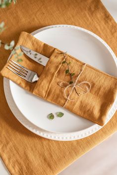 a white plate topped with a fork and knife next to a napkin on top of a table