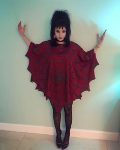 a woman wearing a red dress and black tights is standing in front of a wall