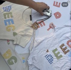 a person is cutting out letters on a white table cloth with a cell phone and camera