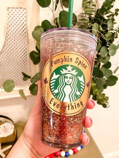 a person holding up a starbucks cup filled with glitter and a green straw in their hand