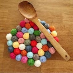 a wooden spoon sitting on top of a pile of crocheted balls