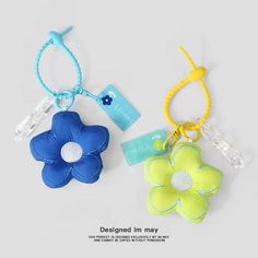 two flower shaped key chains with tags attached to them