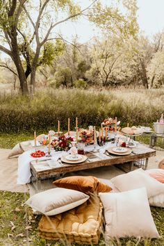 a picnic table set up with food and candles on it in the middle of a field