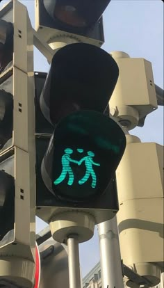 a green pedestrian crossing signal with two people walking across the cross walk sign on it