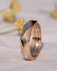 two gold rings with different shapes and sizes on white fabric background, close up view