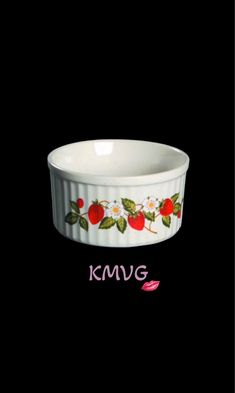 a white bowl with cherries and daisies painted on the side, sitting in front of a black background