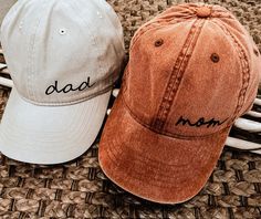 two baseball caps with the word dad and mom written on them sitting next to each other