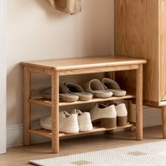 a wooden bench with shoes on it in front of a wall mounted coat rack and door