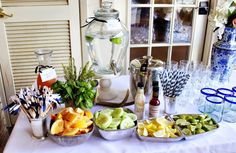 an assortment of fruits and drinks on a table in front of a vase with flowers