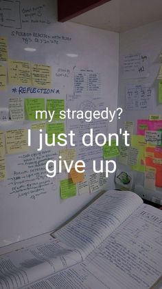 an open book sitting on top of a table next to a whiteboard covered in sticky notes