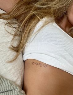 a woman laying in bed with her back turned to the camera and tattoos on her chest