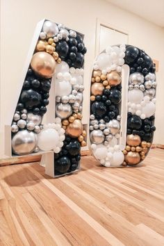 the letters are made out of balloons and other items in black, white, gold and silver colors