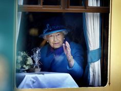 the queen waves from her window as she sits at a table