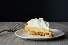 a piece of pie with whipped cream on top sits on a plate next to a fork