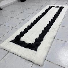 a black and white rug on the floor in front of a tiled area with tile floors