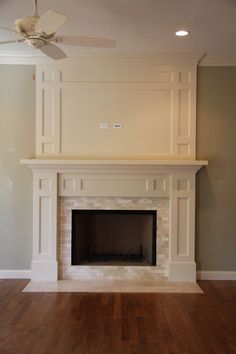 an empty living room with a fireplace and ceiling fan