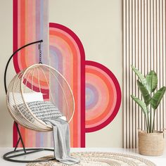 a chair and rug in front of a wall with colorful circles on it, next to a potted plant