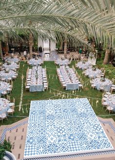 an outdoor venue with tables and chairs set up for a formal dinner under palm trees