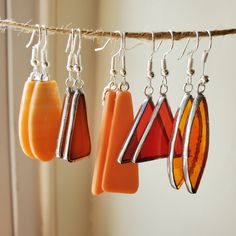 three different colored glass pieces hanging from a line with silver hooks and earwires