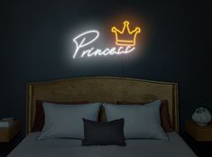 a bed with pillows and a neon sign on the wall above it that says princess