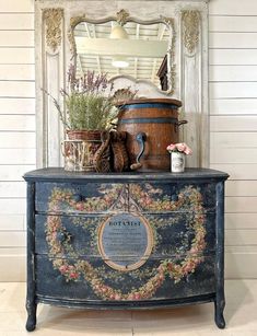 an old chest with flowers and other things on it, in front of a mirror