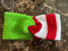 a green and white knitted hat sitting on top of a marble counter next to a red heart