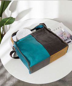 a purse sitting on top of a table next to a magazine and plant in a vase