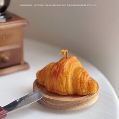 a croissant sitting on top of a wooden plate next to a knife