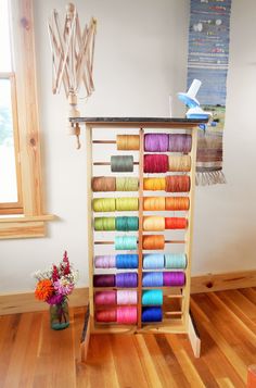 a rack with many different colored spools of thread on top of wooden floors