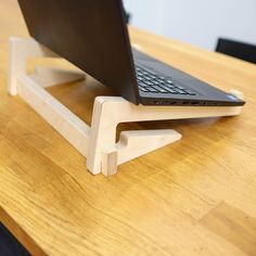 a laptop computer sitting on top of a wooden stand