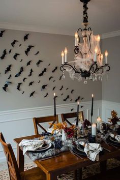 a dining room table is set with candles and place settings for halloween dinner party decorations