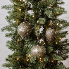 a christmas tree with ornaments hanging from it's branches and lights on the top