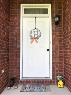 a white door with an orange bow on it and welcome mat in front of it